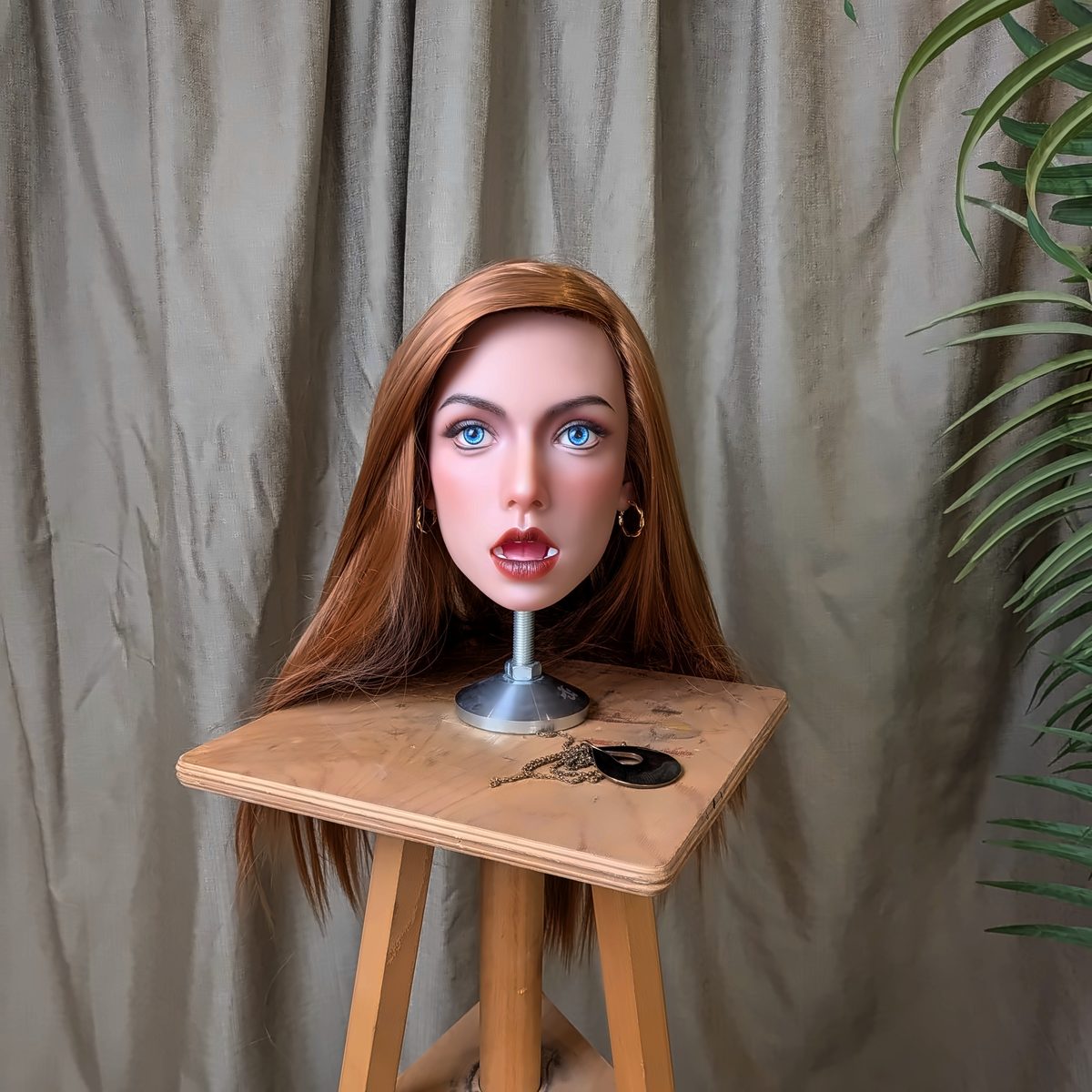 The Copper look with hoop earrings on a wooden stool, a string of pearls on the seat, in front of a grey curtain.