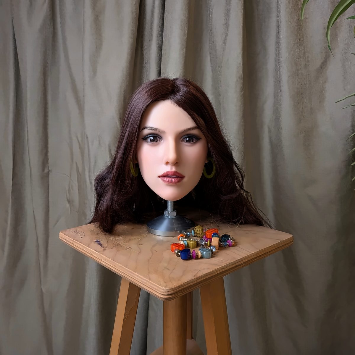 The Brunette look with green hoop earrings on a wooden stool, colourful beads beside the stand.
