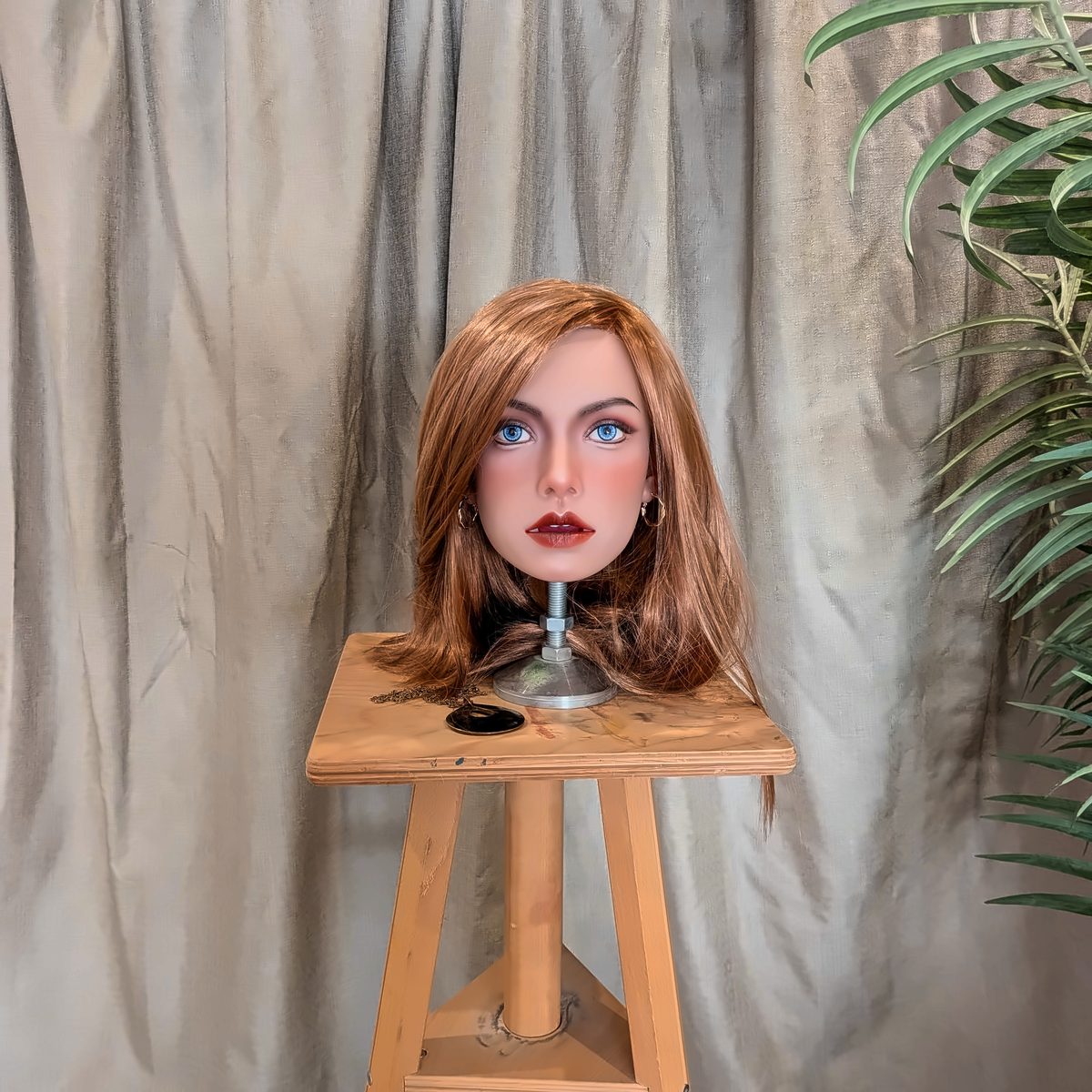 The Ginger look, with a lighter, shorter cut, on a wooden stool in front of a grey curtain.